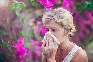 Woman with with allergy symptom blowing nose