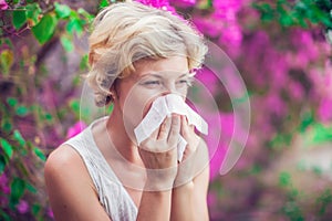 Woman with allergy symptom blowing nose