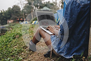 Woman alone in nature using a laptop on a camp site getaway from work or internet addiction concept