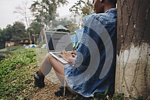 Woman alone in nature using a laptop on a camp site getaway from work or internet addiction concept