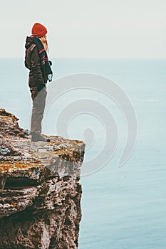 Woman alone standing on cliff edge above sea Travel Lifestyle concept Solitude melancholy emotions