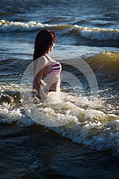 Woman in in american flag bikini in water, sea, waves. Fashion.