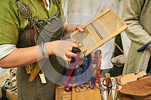 A woman in ancient Byzantine clothing makes yarn and sews from vintage fabric threads. Reconstruction of the events of the Middle