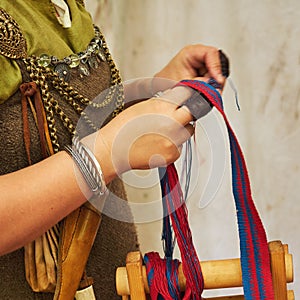 A woman in ancient Byzantine clothing makes yarn and sews from vintage fabric threads. Reconstruction of the events of the Middle
