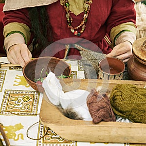 A woman in ancient Byzantine clothing makes yarn and sews from vintage wool. Reconstruction of the events of the Middle Ages in