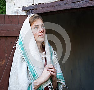 A woman in ancient clothes is standing at the door
