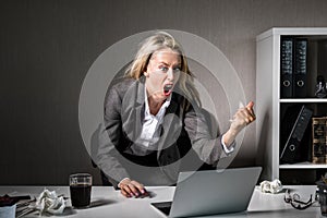 Woman angry at her laptop computer at work