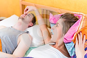 Woman is angry and holds nose of her snoring partner