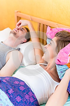Woman is angry and holds nose of her snoring partner