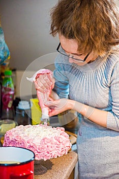 Woman applied the cream on the cake