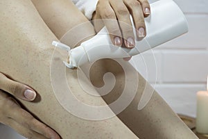A woman applies a moisturizer to the skin of her legs. Problem skin, strawberry legs, chicken skin, hyperkeratosis, keratosis photo