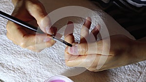 Woman applies a thin layer of protective gel to the fingernails with a brush