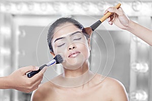 Woman apply cosmetics on her cheek