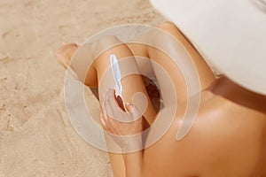 Woman apply sun protection cream on her smooth tanned legs. Skin care.