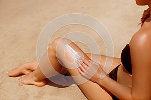 Woman apply sun protection cream on her smooth tanned legs. Skin care.