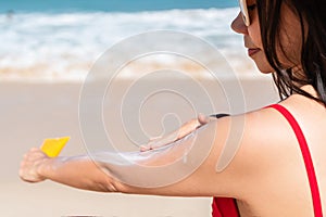 Woman apply sun screen on to her hand on tropical beach. Girl applying sun cream. UV protection summer and holiday concept