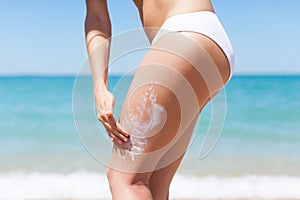 Woman apply sunscreen lotion on hip legs