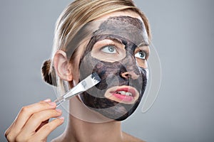 Woman Applying Activated Charcoal Face Mask With Brush photo