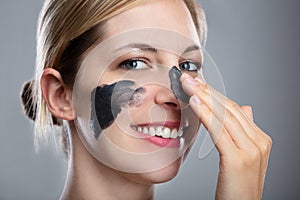 Woman Applying Activated Charcoal Mask On Her Face