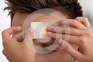 Woman applying adhesive bandage on man`s forehead