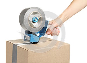 Woman applying adhesive tape on box with dispenser against white background, closeup