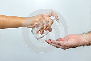 Woman applying alcohol on a man`s hand.