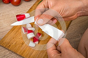 Woman is applying band aid plaster on her finger