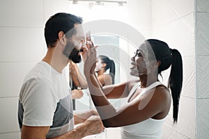 Woman Applying Beauty Mask And Skin Cleanser To Man