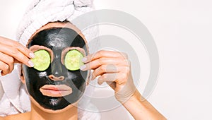 Woman applying black charcoal facial mask. Face skin care.Spa therapy.Copy space