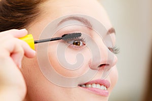 Woman applying black eye mascara to her eyelashes