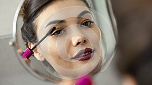 Woman applying black mascara on eyelashes