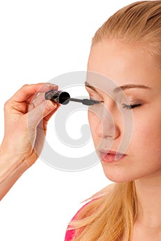 Woman applying black mascara on eyelashes, doing makeup.