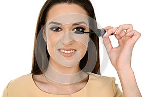 Woman applying black mascara on eyelashes with makeup brush