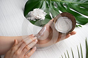 Woman applying body cream with coconut extract