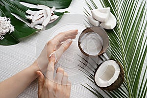 Woman applying body cream with coconut extract