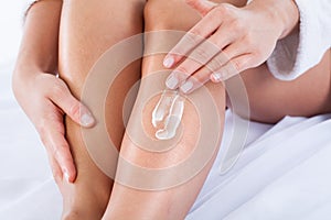 Woman applying body lotion on skin