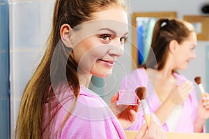 Woman applying bronzing powder with brush to her skin