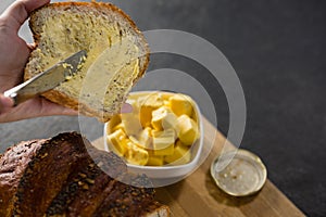 Woman applying butter over multigrain bread slice