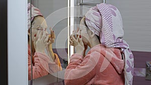 Woman applying cosmetic face mask in bathroom. Skincare spa. Facial mask