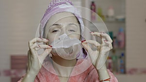 Woman applying cosmetic face mask in bathroom. Skincare spa. Facial mask