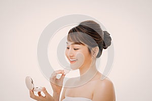 Woman applying cosmetic powder puff on her faceon color background.