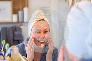 Woman applying cram on her face after shower photo