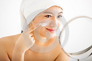 Woman applying cream lotion on face