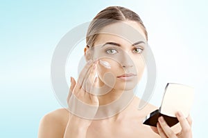 Woman applying cream onto her face