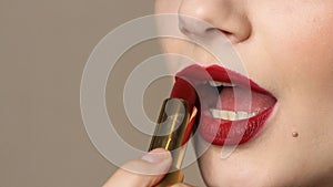 Woman applying deep red lipstick on the lips.  Close up view of beauty and fashion concept