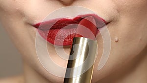 Woman applying deep red lipstick on the lips.  Close up view of beauty and fashion concept