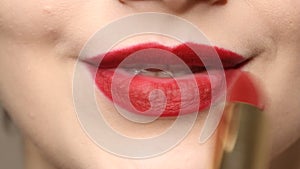 Woman applying deep red lipstick on the lips.  Close up view of beauty and fashion concept