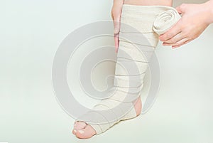 Woman applying elastic compression bandage as a thrombosis prevention after varicose surgery