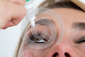Woman Applying Eye Drop Over White Background