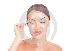 Woman applying eyelash serum essential oil on eyelashes with makeup mascara brush